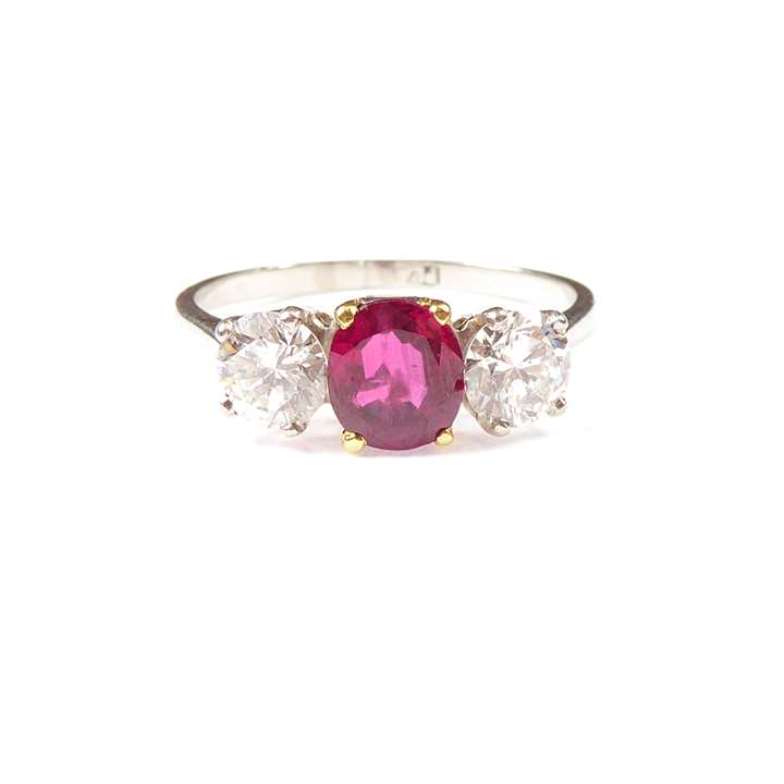 Ruby and diamond three stone ring, claw set with an oval cut Burma ruby